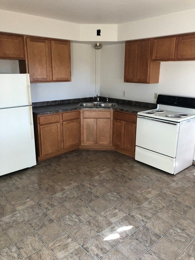 an empty kitchen with white appliances and wooden cabinets