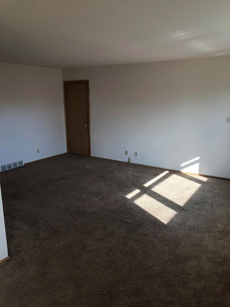 an empty living room with white walls and a door