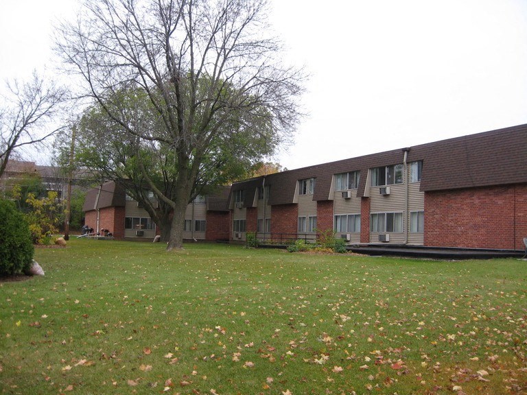 an apartment building with a yard and a tree
