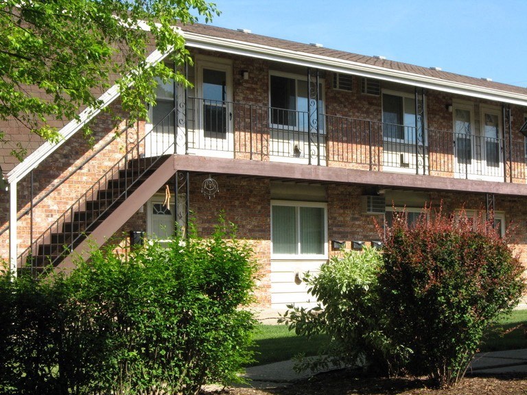 the front of a brick building with stairs and a balcony