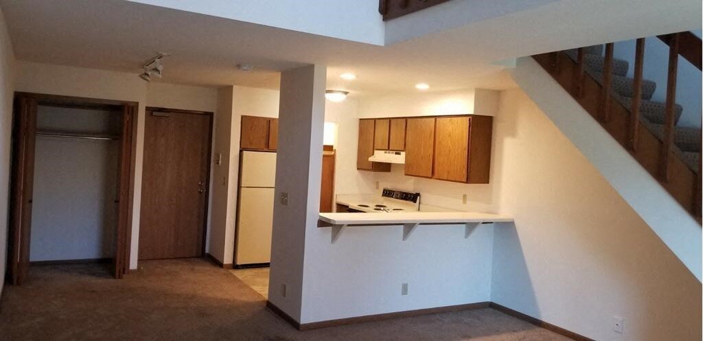 an empty kitchen with a refrigerator and a staircase