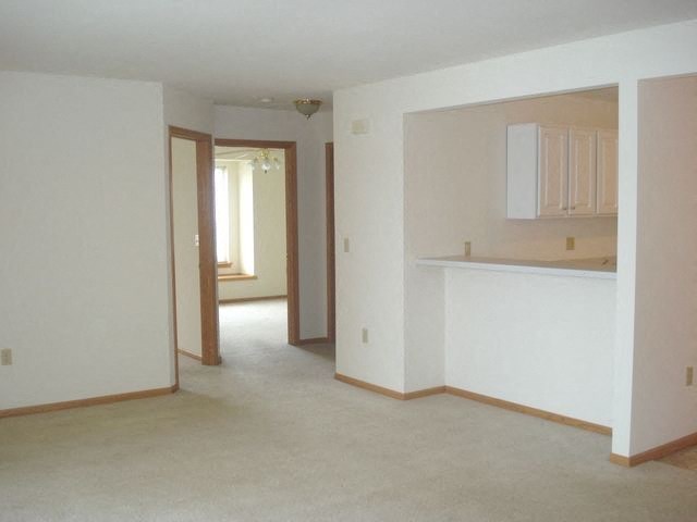 an empty living room with an empty kitchen and