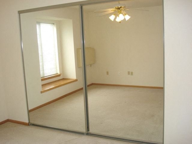 an empty room with a ceiling fan and a mirror