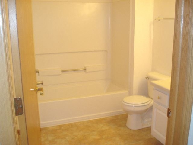 a white bathroom with a toilet and a bath tub