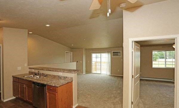 an empty living room with a kitchen with a sink