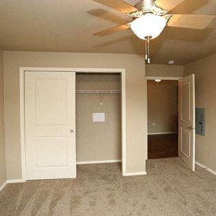 an empty bedroom with a ceiling fan and a closet