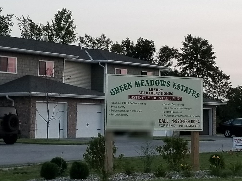 a sign for green meadows estates is shown in front of a house
