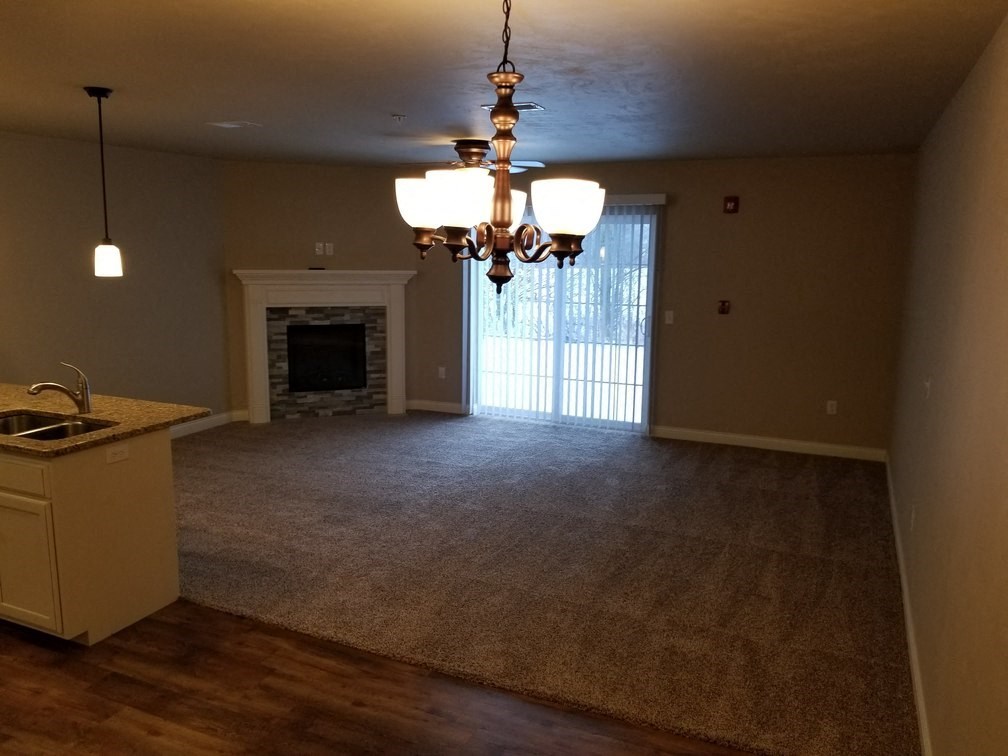 an empty living room with a fireplace and a chandelier