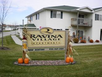a sign in front of a house with pumpkins on it