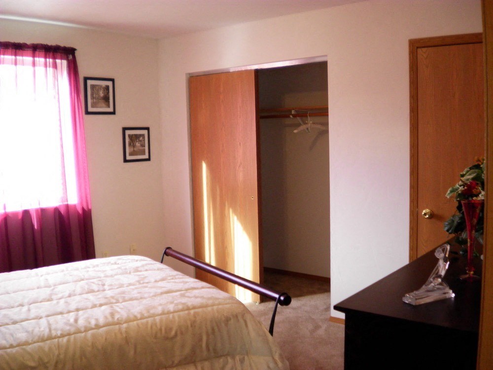 a bedroom with a bed and a closet and a door to a bathroom