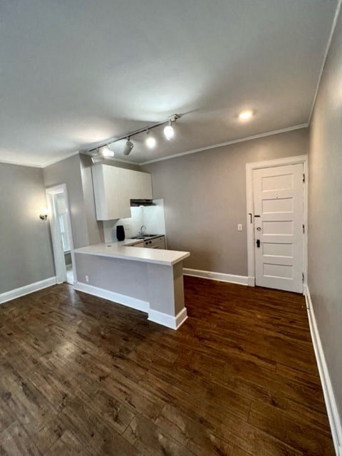 an empty living room with a kitchen and a door
