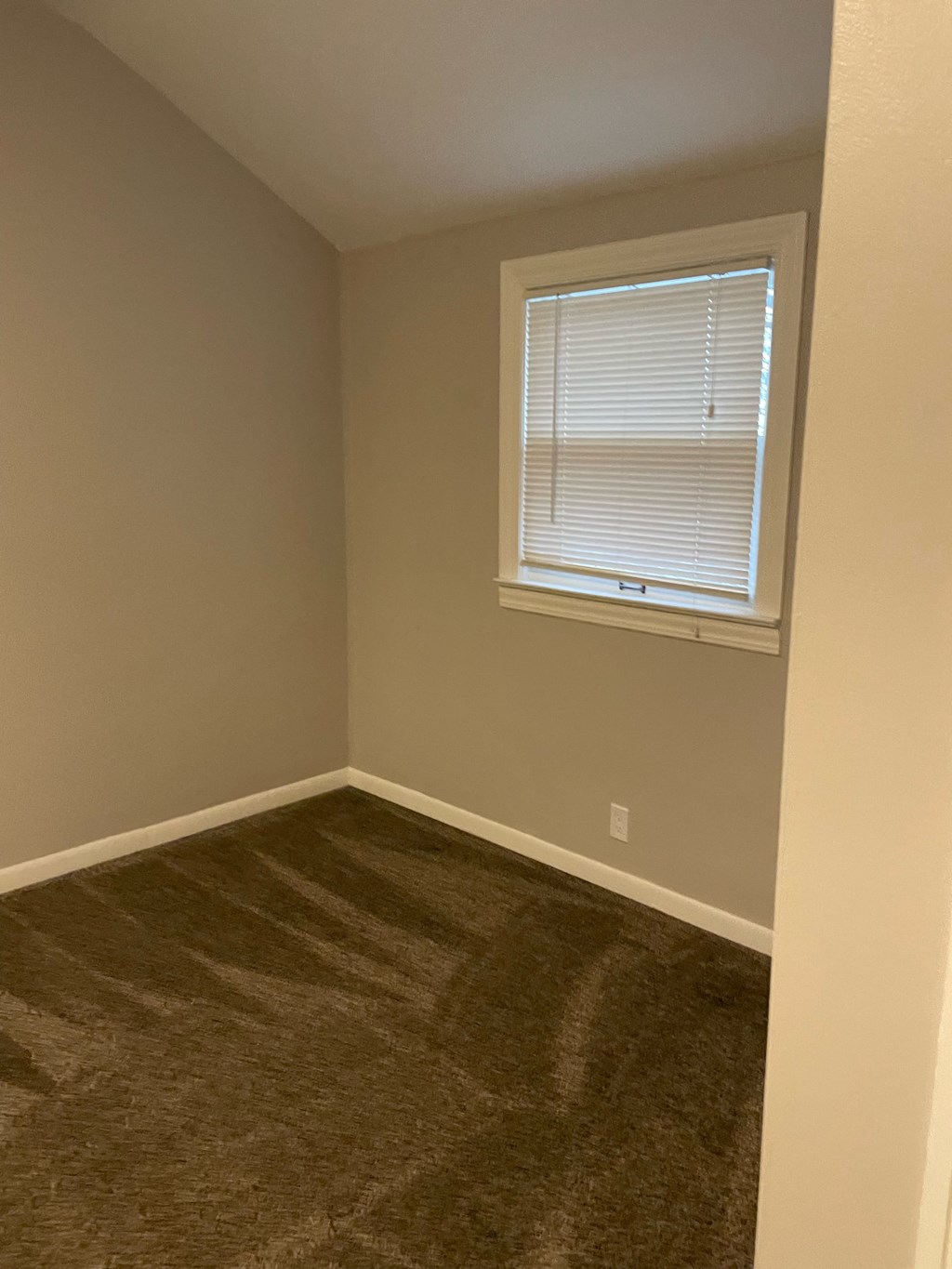 an empty room with a window and a carpet