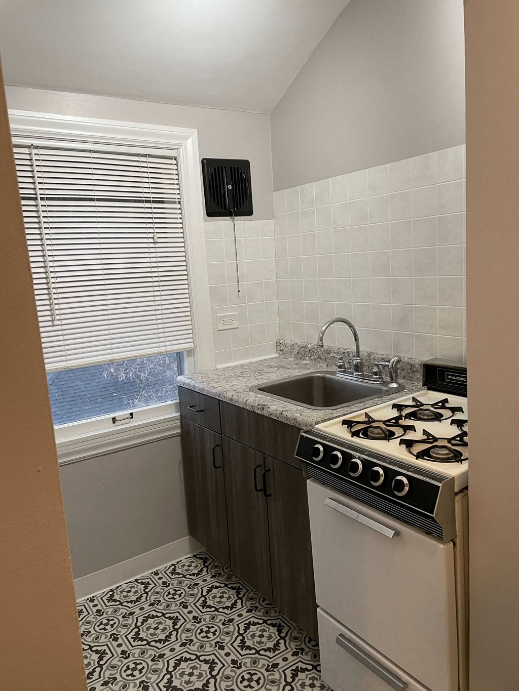 a small kitchen with a stove sink and a window