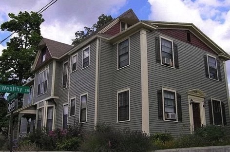 a gray house with a street sign in front of it