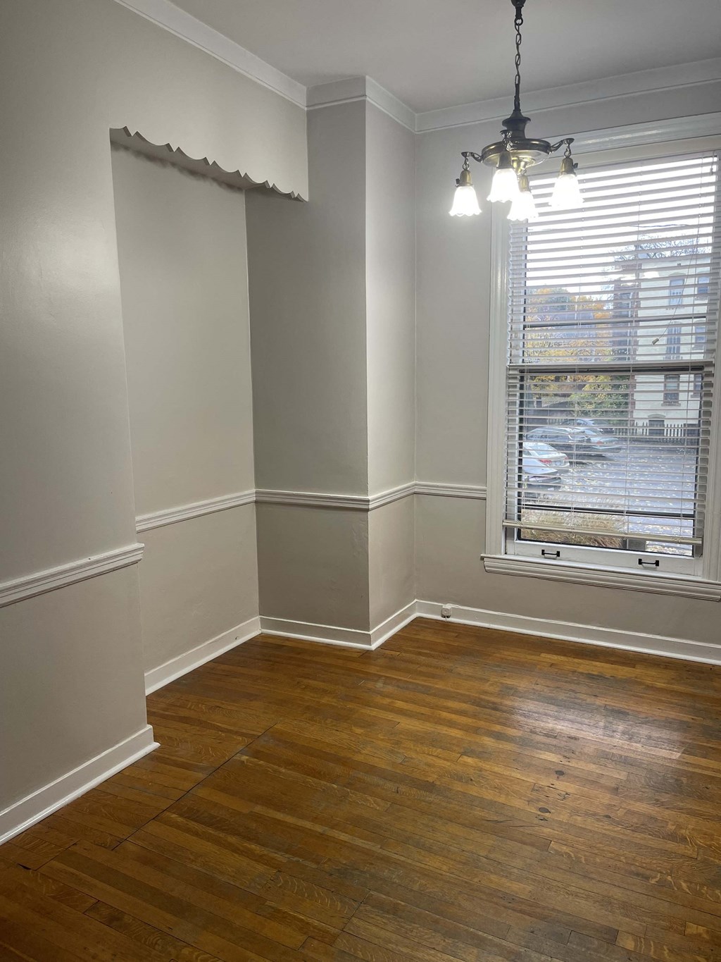a corner of a room with a window and wooden floors