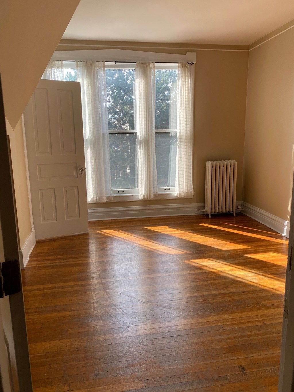 an empty room with wooden floors and large windows