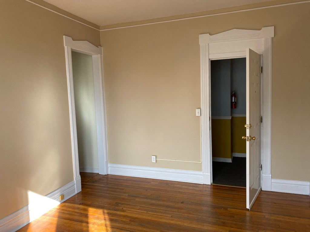 a living room with wood floors and a door open to a hallway