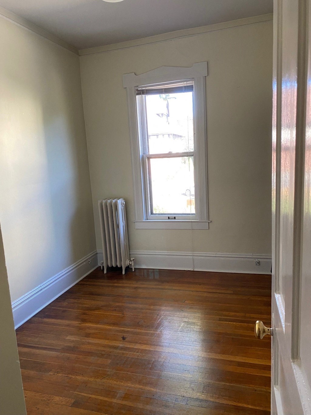 an empty room with a window and wooden floors