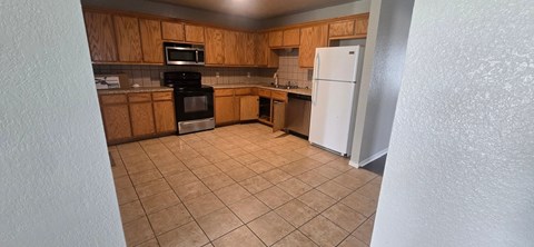 A kitchen with a white refrigerator and wooden cabinets.
