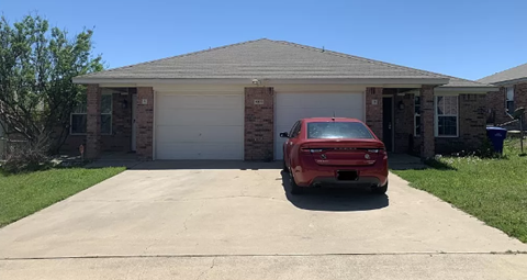 A red car is parked in front of a house.