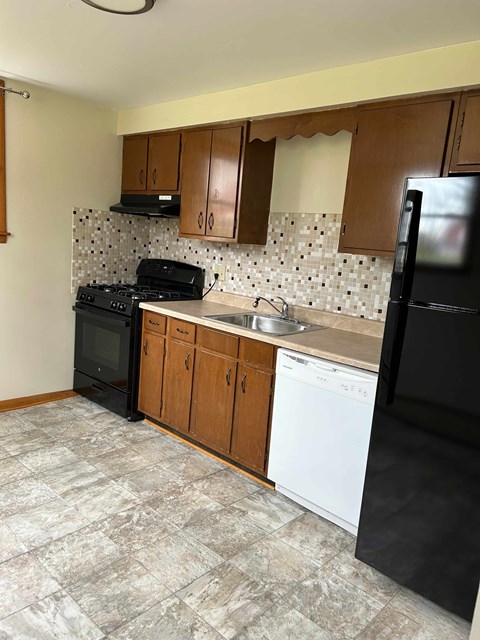 A kitchen with black appliances and wooden cabinets.