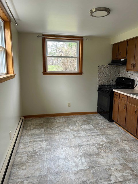 A kitchen with a black stove top oven and wooden cabinets.