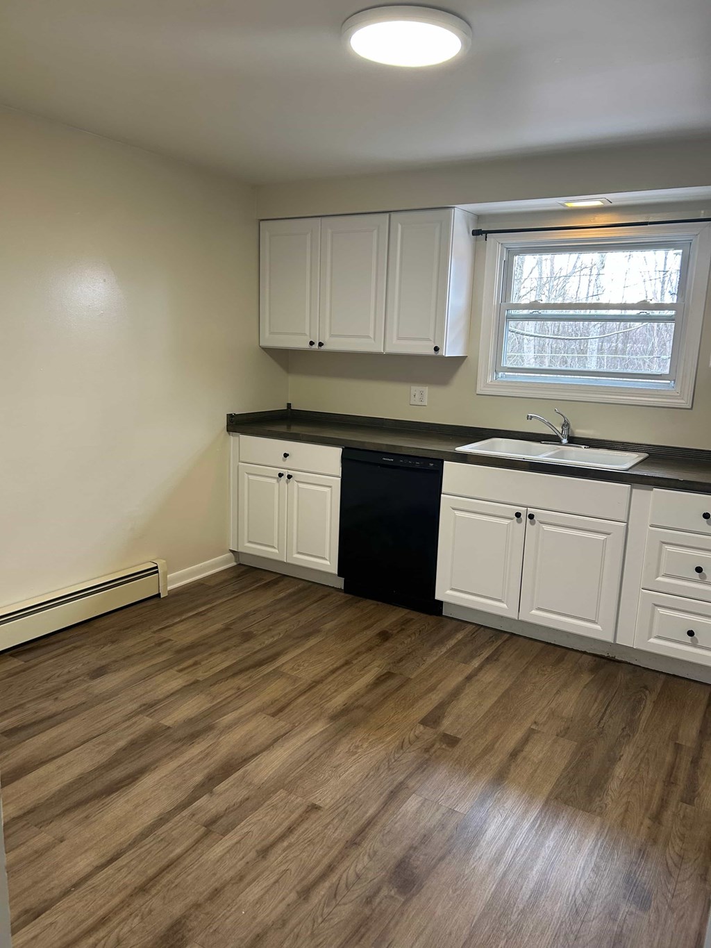 A kitchen with white cabinets and a black dishwasher.