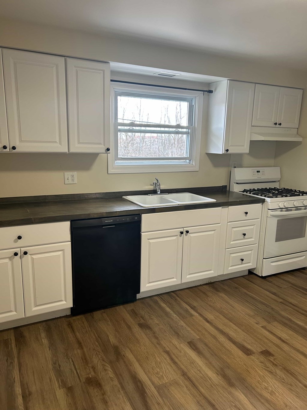 A kitchen with white cabinets and a black dishwasher.