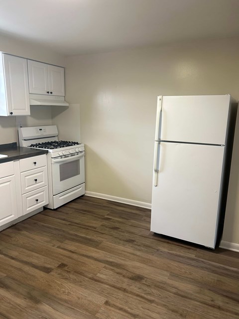 A kitchen with a white fridge, stove and cabinets.