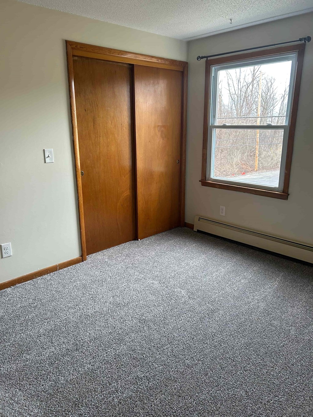 A room with a carpeted floor, a window, and a door.