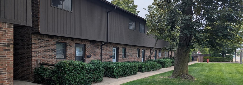A tree is in front of a building with a green lawn.