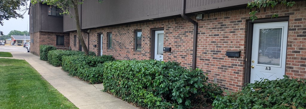 A brick building with a green hedge in front.