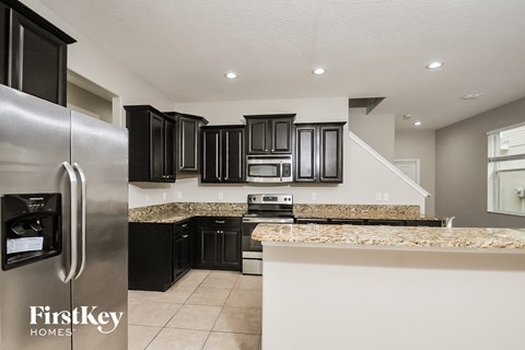A kitchen with a stainless steel refrigerator and black cabinets.