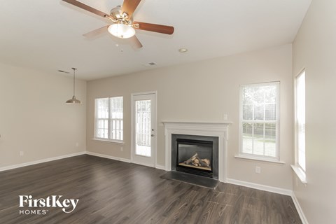 A spacious room with a fireplace and a ceiling fan.
