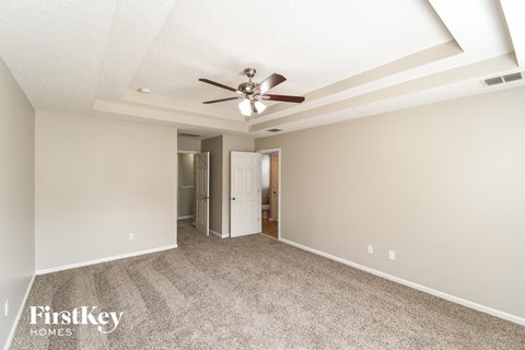 A spacious room with a ceiling fan and a doorway leading to another room.