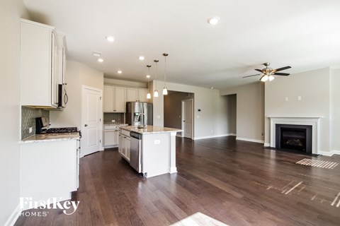 an open kitchen and living room with white cabinets and a fireplace