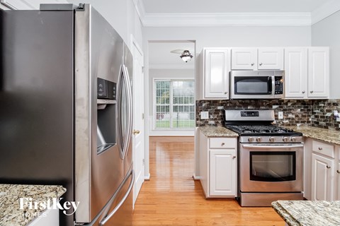 A kitchen with a stainless steel refrigerator and white cabinets.