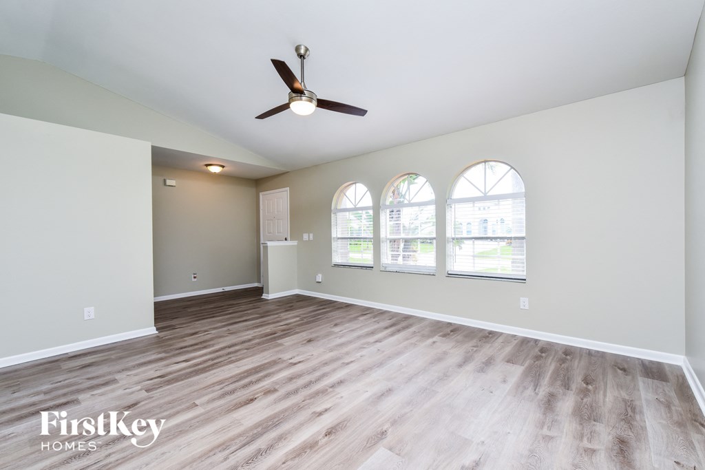 A spacious room with a ceiling fan and hardwood flooring.