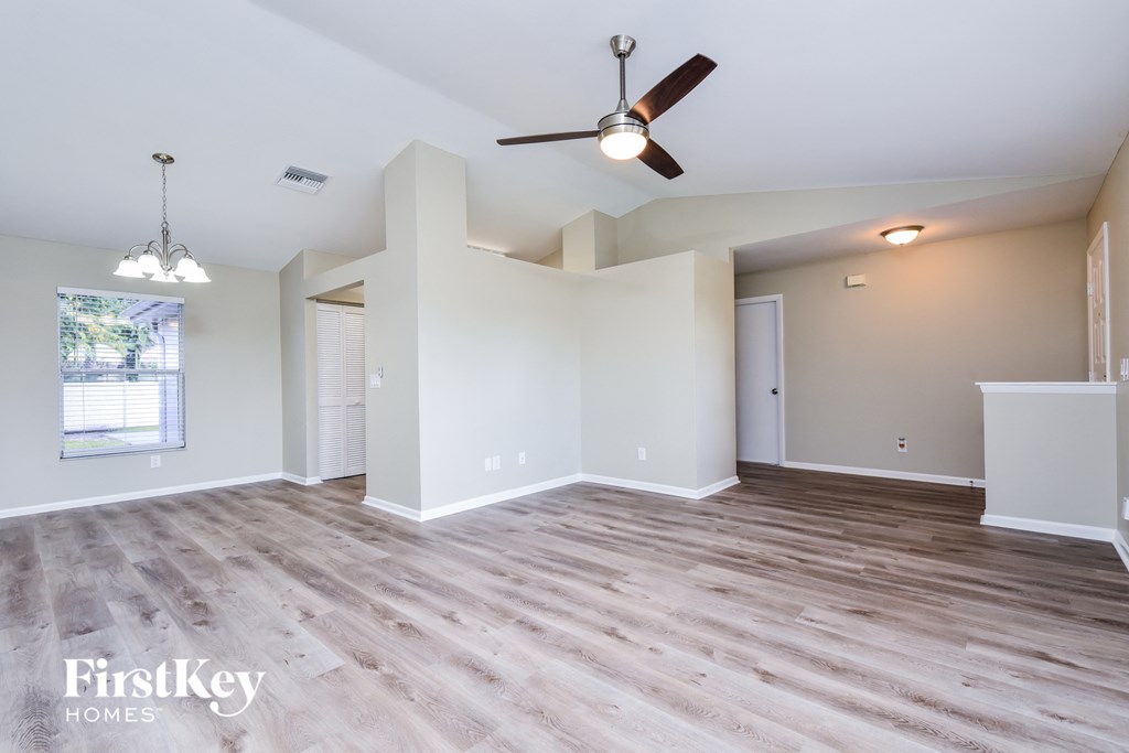 A spacious room with a ceiling fan and lighting fixtures.