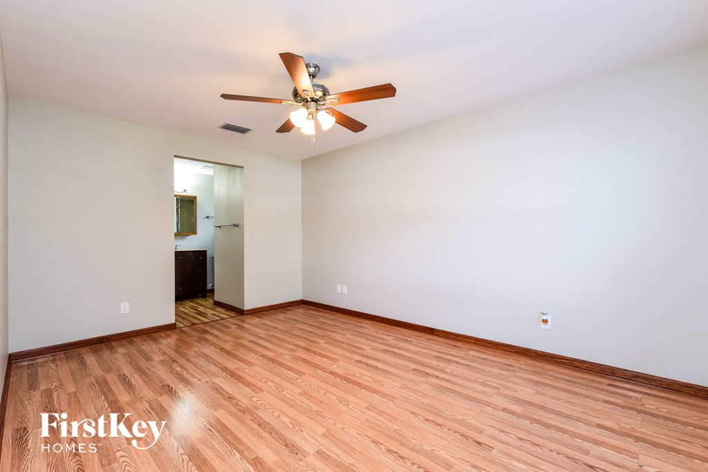 A room with a ceiling fan and wooden flooring.