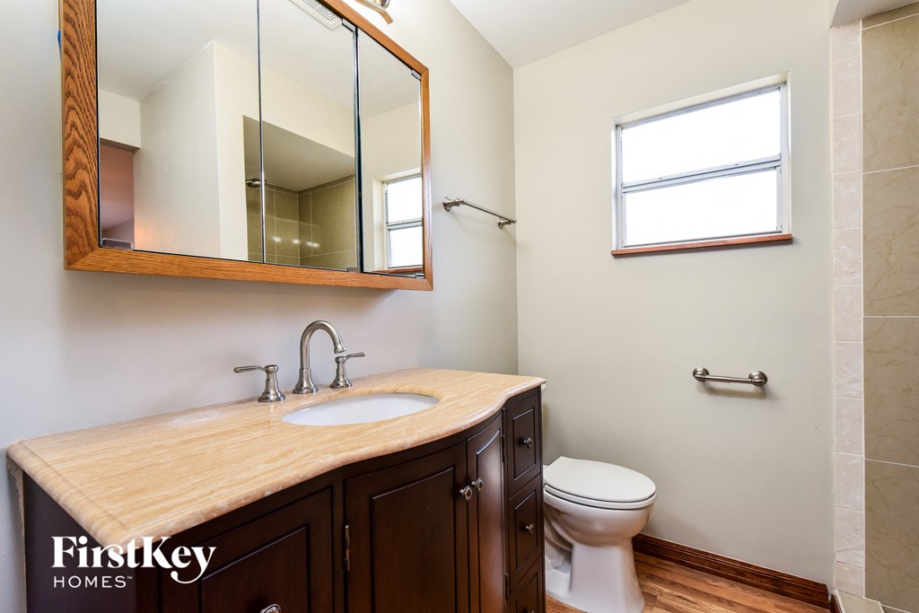 A bathroom with a wooden counter top and a mirror above it.