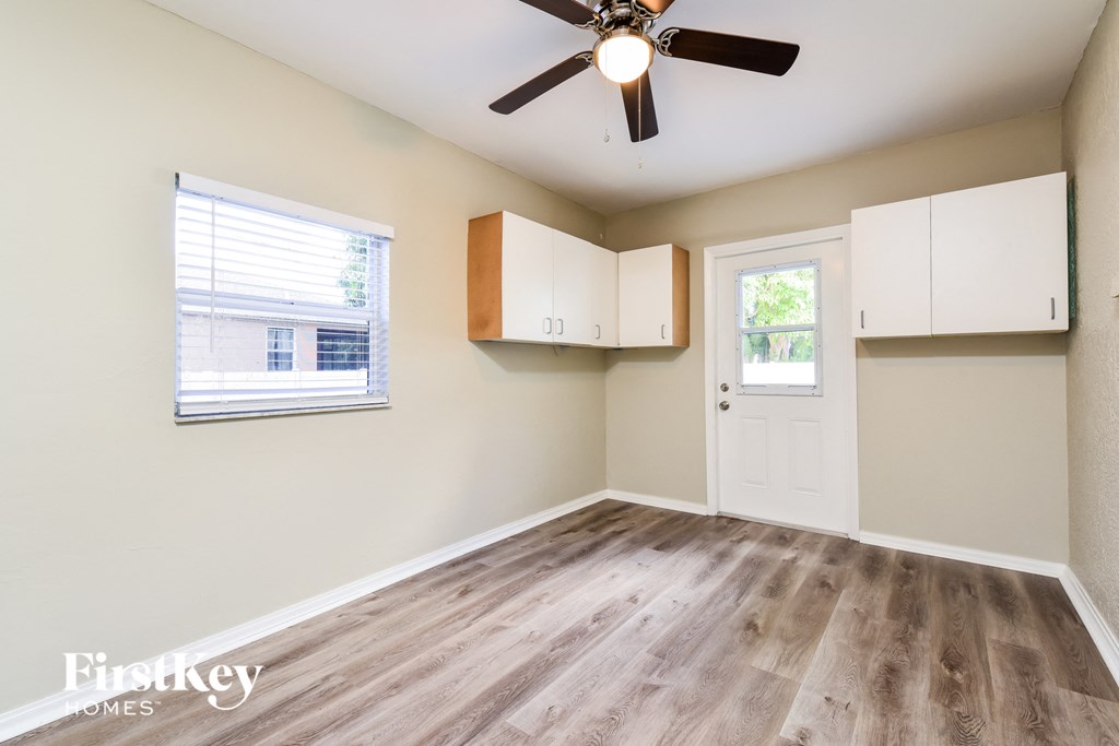 A room with a ceiling fan, wooden flooring, and a window with blinds.