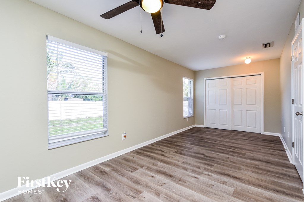 A room with a ceiling fan and a window with blinds.