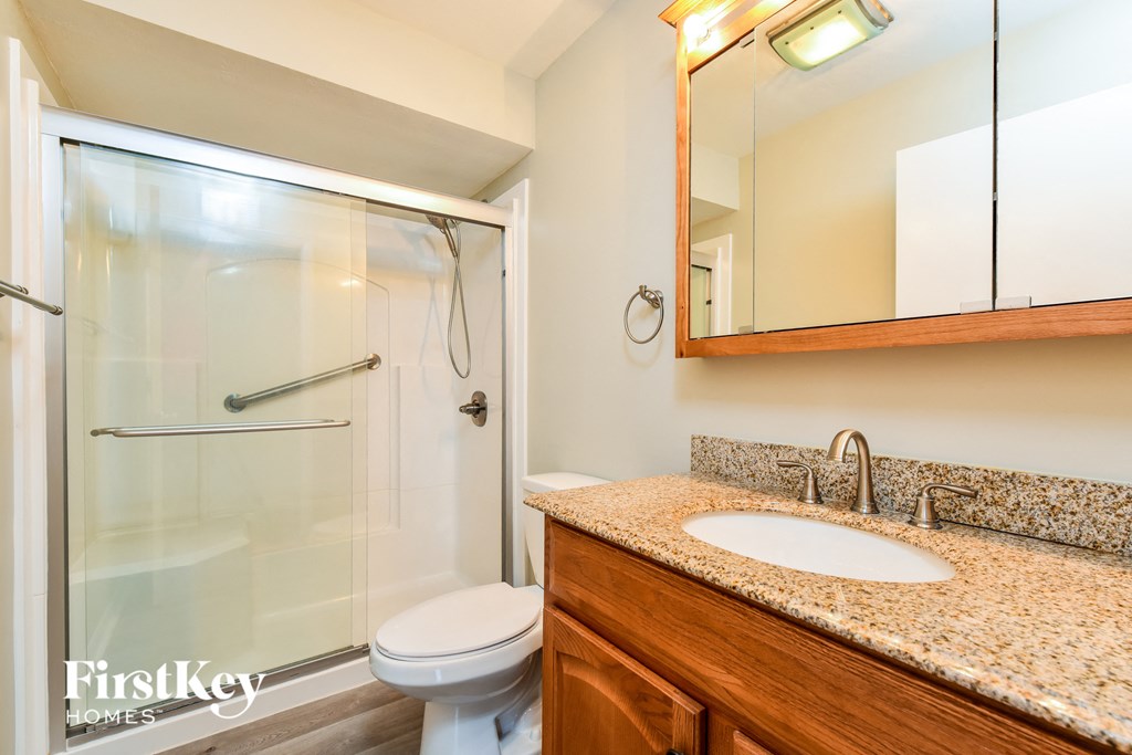 A bathroom with a granite countertop and a glass shower.