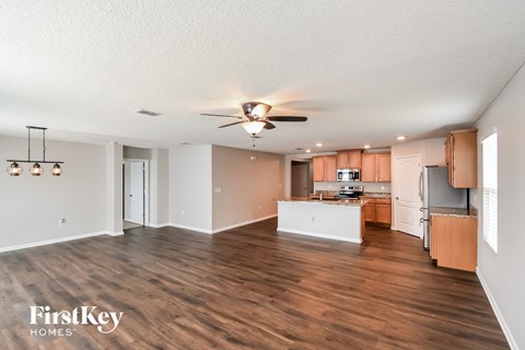 A spacious kitchen with wooden floors and a ceiling fan.