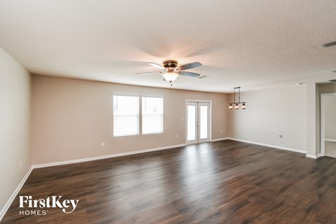 A spacious room with wooden floors and a ceiling fan.