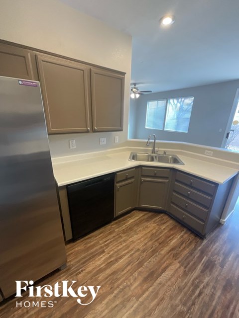 A kitchen with wooden floors and a stainless steel refrigerator.