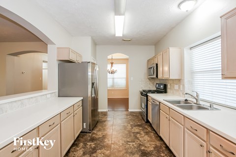 A kitchen with brown tiled floors and beige cabinets.