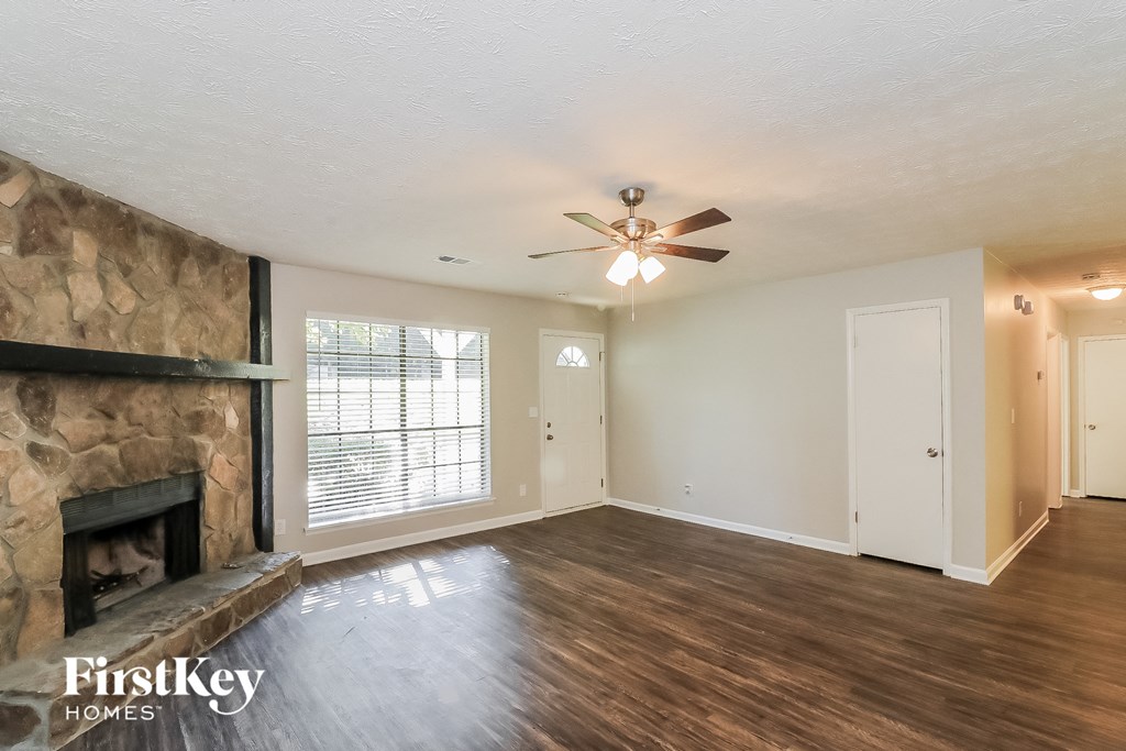 an empty living room with a fireplace and a ceiling fan