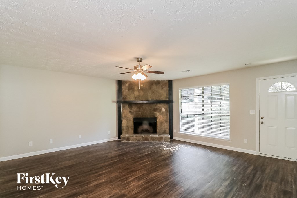 an empty living room with a fireplace and a ceiling fan